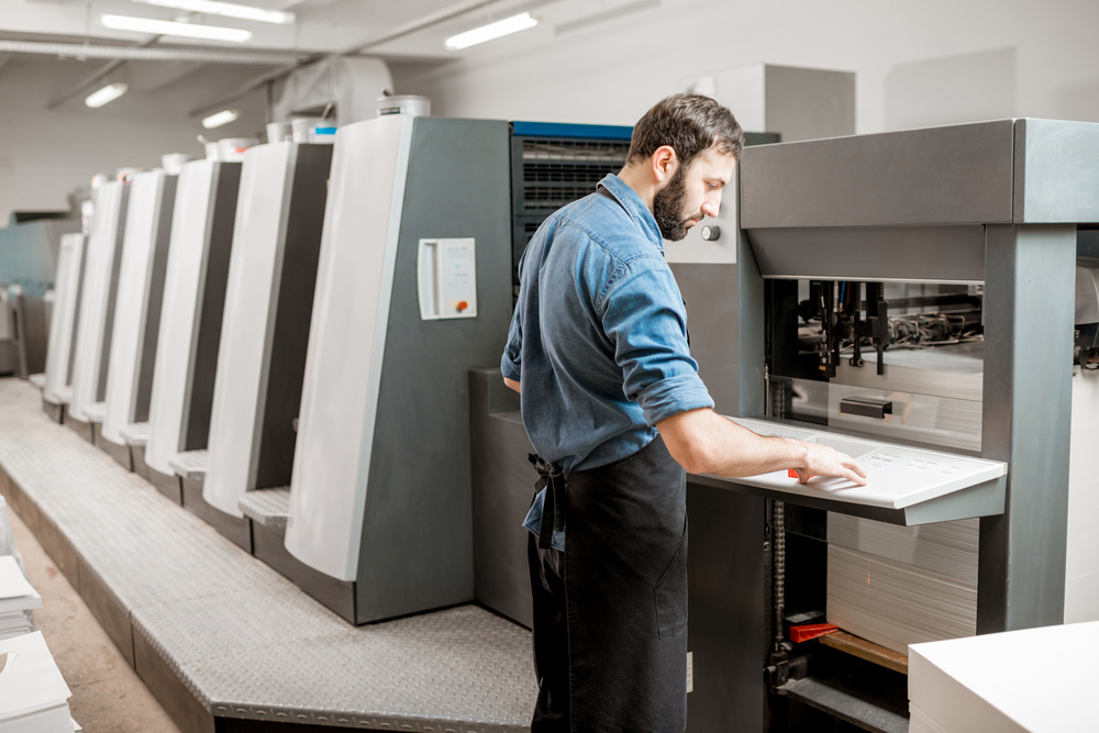 A technician inspects a large-format offset press in action. These machines are engineered to deliver unrivaled consistency across thousands of impressions, making them indispensable for mass production.